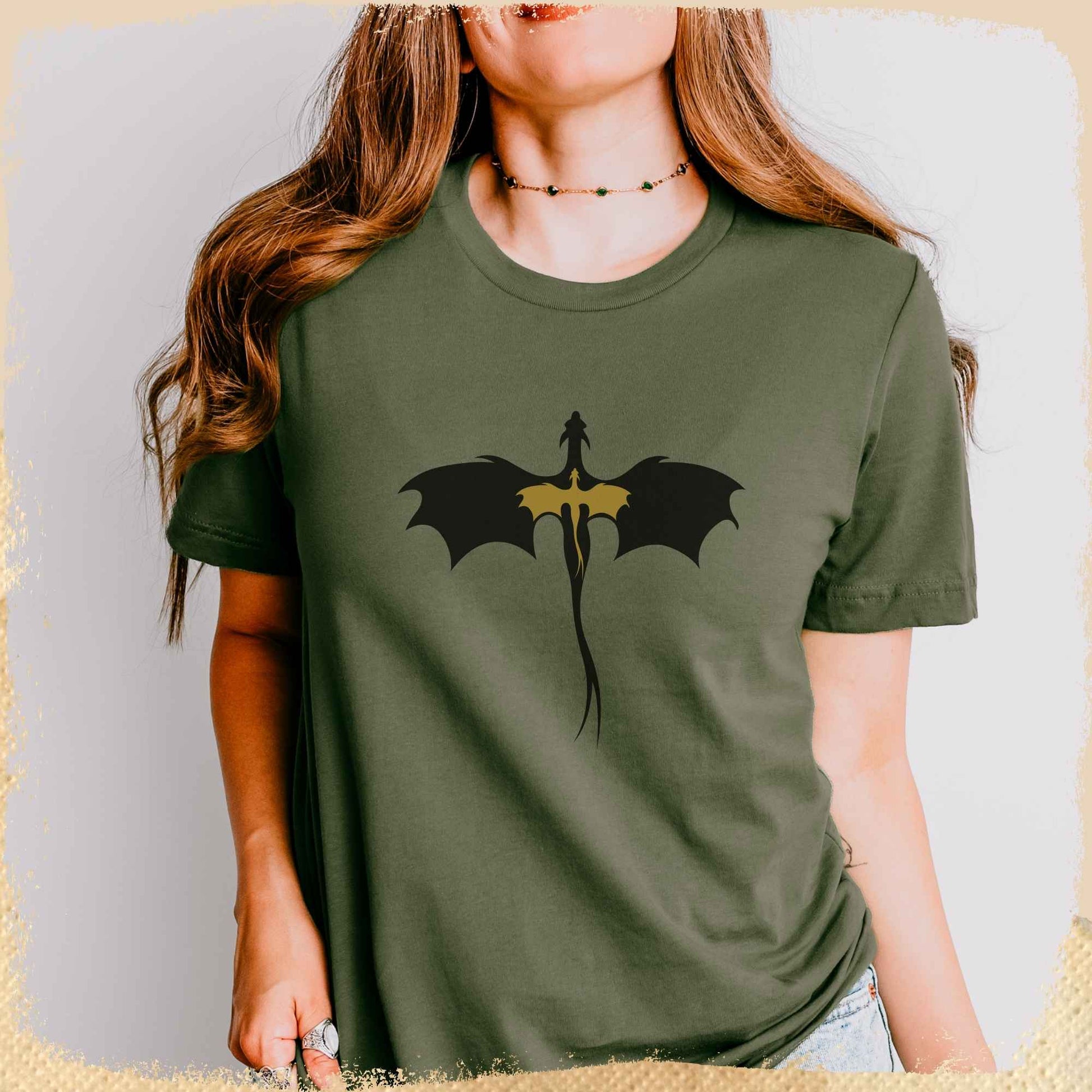 Eine junge Frau trägt ein grünes T-Shirt auf dem die Silhouetten eines schwarzen und eines goldenen Drachen abgebildet sind.